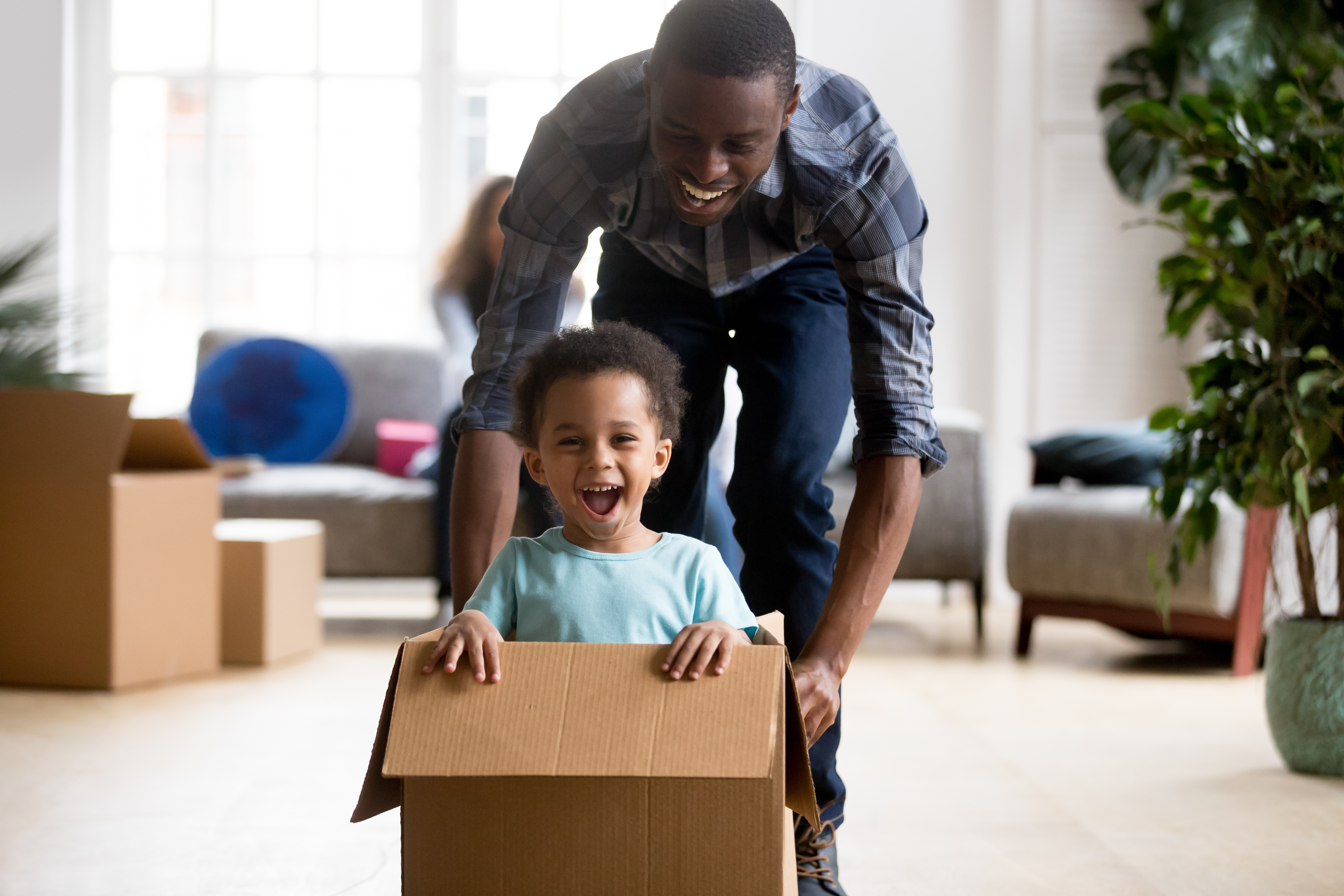 man pushing child in cardboard box